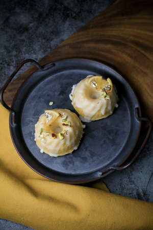 Lemon cake with sugar sweet icing on yellow and black background. Cake with citrus, poppy, traditional american cuisine in dark toneの写真素材