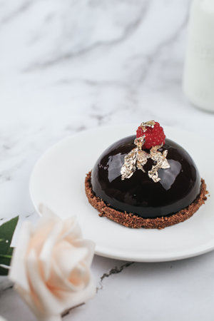 Chocolate mousse Cake with berries with rose flower on marble table. Delicious homemade cake.の写真素材