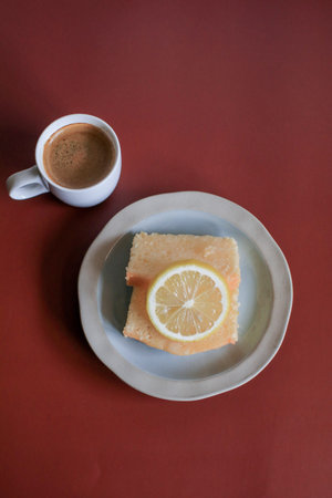 Lemon pound cake with white a cup of coffee on red background. Home baked sliced loaf cake. Classic...