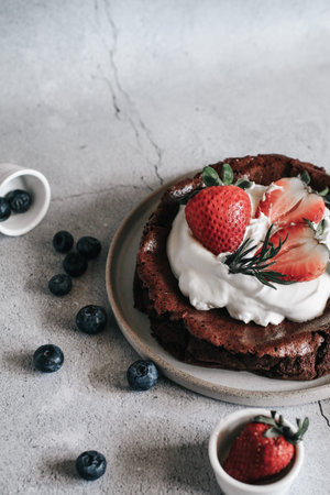 Flourless chocolate cake with whipping cream and strawberry on concrete background. Homemade cake...