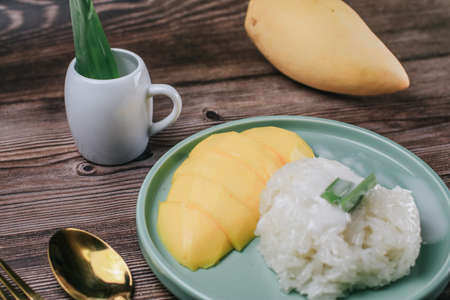 Delicious mango sticky rice serve with coconut milk on wooden table. Popular traditional dessert of Thailand.の写真素材