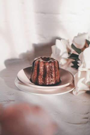 Caneles de bordeaux with rose under sunlight. French pastry Canele rum and vanilla flavor thick caramelized crustの写真素材