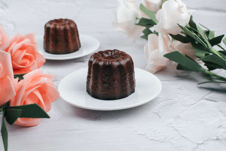 Caneles de bordeaux with rose traditional French sweet dessert on white table background. under sunlight. French pastry Canele rum and vanilla flavor thick caramelized crust.の写真素材