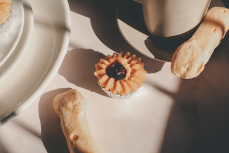 Tasty cookies with jam on top in white plates and hot coffee with window light. Breakfast. Close up....