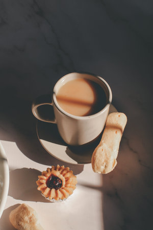 Tasty cookies with jam on top in white plates and hot coffee with window light. Breakfast. Close up....