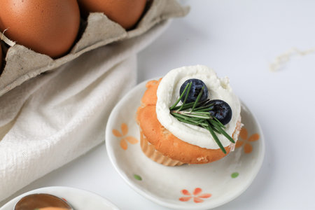Vanilla cupcakes topped with fresh blueberries. Homemade baked goods. Confectioner decorating...