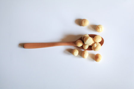 Macadamia nuts in wooden spoon on white background. Healthy product. Macadamia nuts are a source of protein packed with healthy vitamins.の写真素材