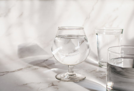 Sunlight through glass of water make light and shadow make a beautiful pattern by refraction of light on white background.の写真素材