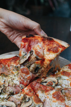 Close up delicious freshly baked small pizza with melted cheese mushrooms and tomato sauce on wooden...