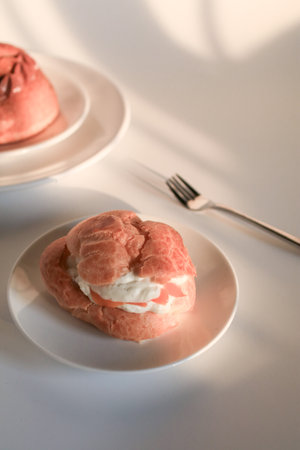 Homemade choux pastry with cream. on white background under sunlight. Selective focus, copy space. Popular French dessert.の写真素材