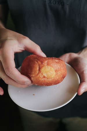 Hand pick doughnuts with Creamy Lemon Filling Dusted on white plate. copy space for your text. Snack food and dessert.の写真素材