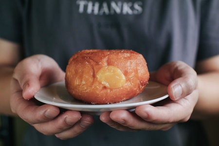 Hand pick doughnuts with Creamy Lemon Filling Dusted on white plate. copy space for your text. Snack...