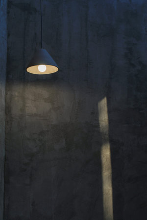 Hanging Light Bulb glowing in dark. Empty Concrete Room Interior.