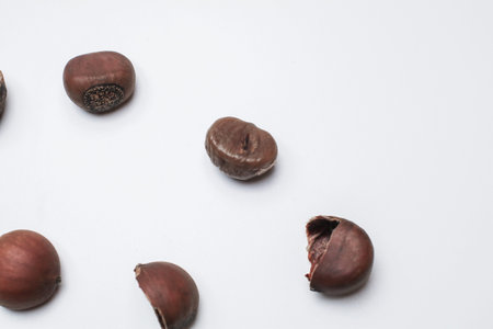 Chestnuts on white background. Pile of fresh chestnuts ready to roast. Top view, copy space. Flat...