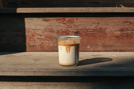 Coffee with milk under sunlight on wooden background. Light and shadow in morning breakfast minimal...
