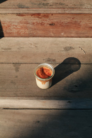 Coffee with milk under sunlight on wooden background. Light and shadow in morning breakfast minimal concept.の写真素材