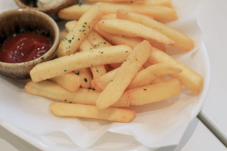 Tasty french fries potato with ketchup on white paper. Hot fast food. Fry delicious snack.