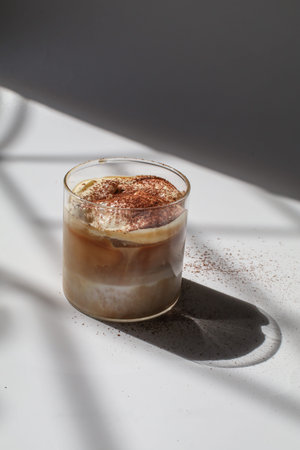Iced coffee latte on white background under early morning sun light. Morning breakfast minimal...