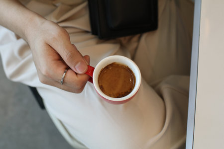 Hand man holding hot coffee espresso in red cup on white table with copy space. Morning cup of coffee.の写真素材