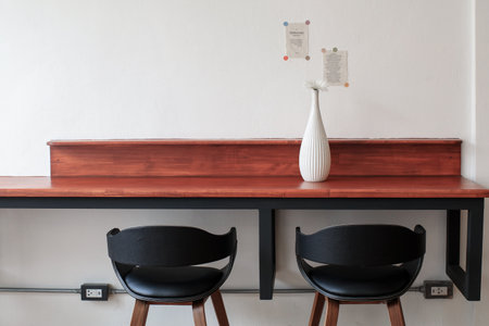 Flower in white glass vase on work wooden table in front of wall. Minimal cozy counter mockup design for product presentation backgroundの写真素材