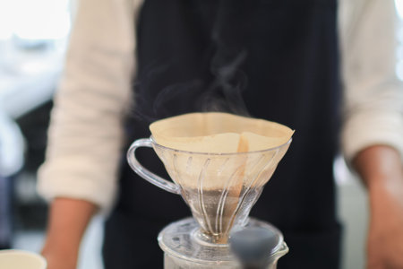 Barista coffee dripper and pour over filter with ground coffee in the funnel. Working in restaurant...