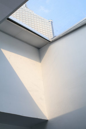 Building a glass roof sky with bright sunshine. White wall interior with big window. Sunny day...