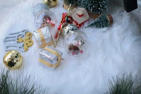 Christmas decoration on white carpet. Gift box with glossy ball and pine cone on fluffy rug. Christmas and new year party holiday vacation.の写真素材
