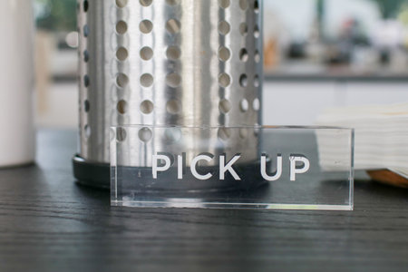 Pick up sign on the black counter with stainless box and straw in coffee shop. Signs and symbols.