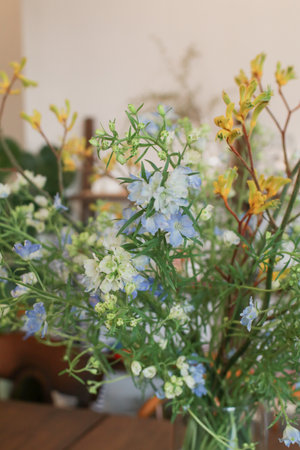 Beautiful bouquet of wild summer yellow flowers in vase. Spring background. Wildflowers in a small glass vase on the table.の写真素材