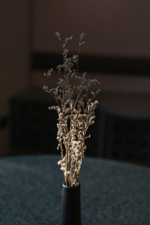 Dry grass bouquet flower in vase with warm shadows from sunlight on wooden table. Scandinavian vase on the table with copy space, minimal aesthetic styleの写真素材