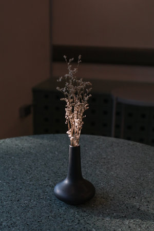 Dry grass bouquet flower in vase with warm shadows from sunlight on wooden table. Scandinavian vase on the table with copy space, minimal aesthetic styleの写真素材