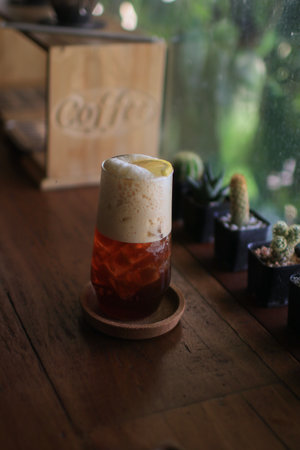 Black coffee mixed lemon juice and lemon slices in a glass. Summer refreshing. Trendy coffee mocktail with sour lemon taste tonicの写真素材