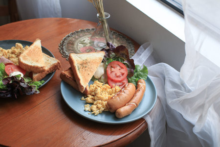 American Breakfast egg ,ham, sausages, bacon, tomato, toasts bread and salad on wooden table. Eating...
