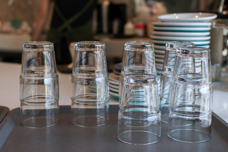 Stacks of empty glasses on bar counter in cafe. Piles of upside down drinking water glasses. Preparing dishes for servingの写真素材