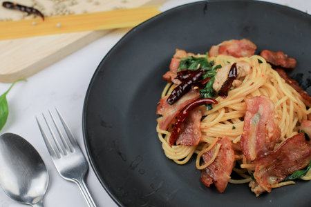 Spaghetti with Dried Chili, basil and Bacon on white table. Traditional Popular menu classic italian cuisine dish. Delicious spicy food.の写真素材