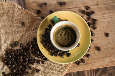 Hot coffee in green cup with coffee beans on old wooden background. Morning breakfast.の写真素材
