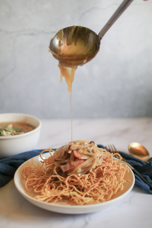 Fried egg noodles in Thick Gravy with pork in white plate. Chinese food. Famous street food menu in Asia.の写真素材