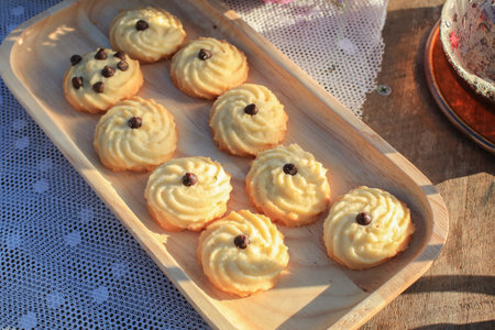 Butter cookie on wooden tray eating coffee under morning sunlight and purple flower on table....