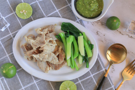 Boiled Pork with Lime Garlic, kale and Chili Sauce in white plate. Thai hot and spicy food. Healthy eating, Asian cuisine, and sustainable dining.の写真素材