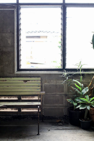 Grungy Wooden bench chair in abandon building interior with cement wall and broken window. Vintage...