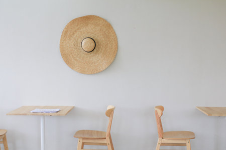Wooden chairs and table in bright modern interior with wicker big hat on white wall.  Minimal living room.の写真素材