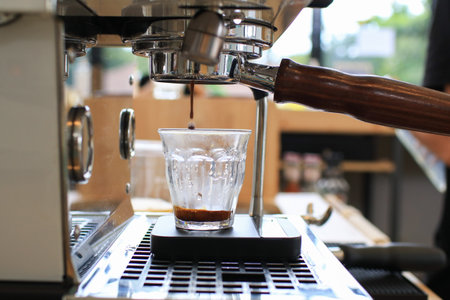 Espresso coffee extraction from coffee machine. Beautiful crema pouring through the bottomless portafilter. Barista working in cafe.の写真素材