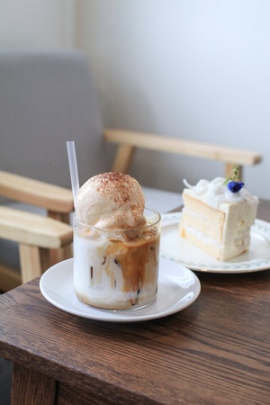 Ice latte coffee with vanilla ice cream on top and coconut cake on wooden table. Dessert in cafe.の写真素材