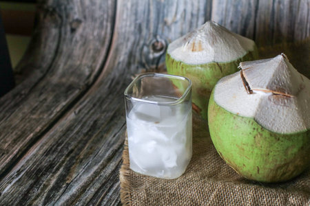 Fresh coconut juice on wooden background. Organic healthy tropical drink.
