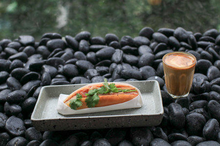 Banh Mi Vietnamese Sandwich, grilled pork and fresh vegetable eating with coffee on black rock in coffee shop.の写真素材