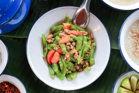 Stir Fried Green Peas with pork and carrot in vintage metal white plate. Homemade food Thai styleの写真素材