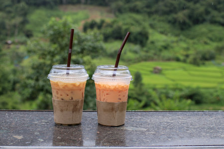 Iced thai tea on wooden table with mountain landscape view. Holiday vacation relax in nature.の写真素材
