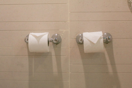 Toilet tissue paper in holder on tiled wall in bathroom. Modern restroom interior detail.の写真素材