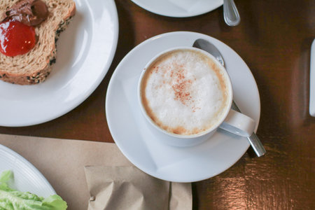 Hot coffee latte cappuccino with milk foam on wooden table for morning breakfast. Refreshing drink.の写真素材