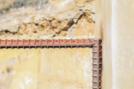 Rusty steel rods on cement wall. Construction material under sunlight. Provide tensile strength...